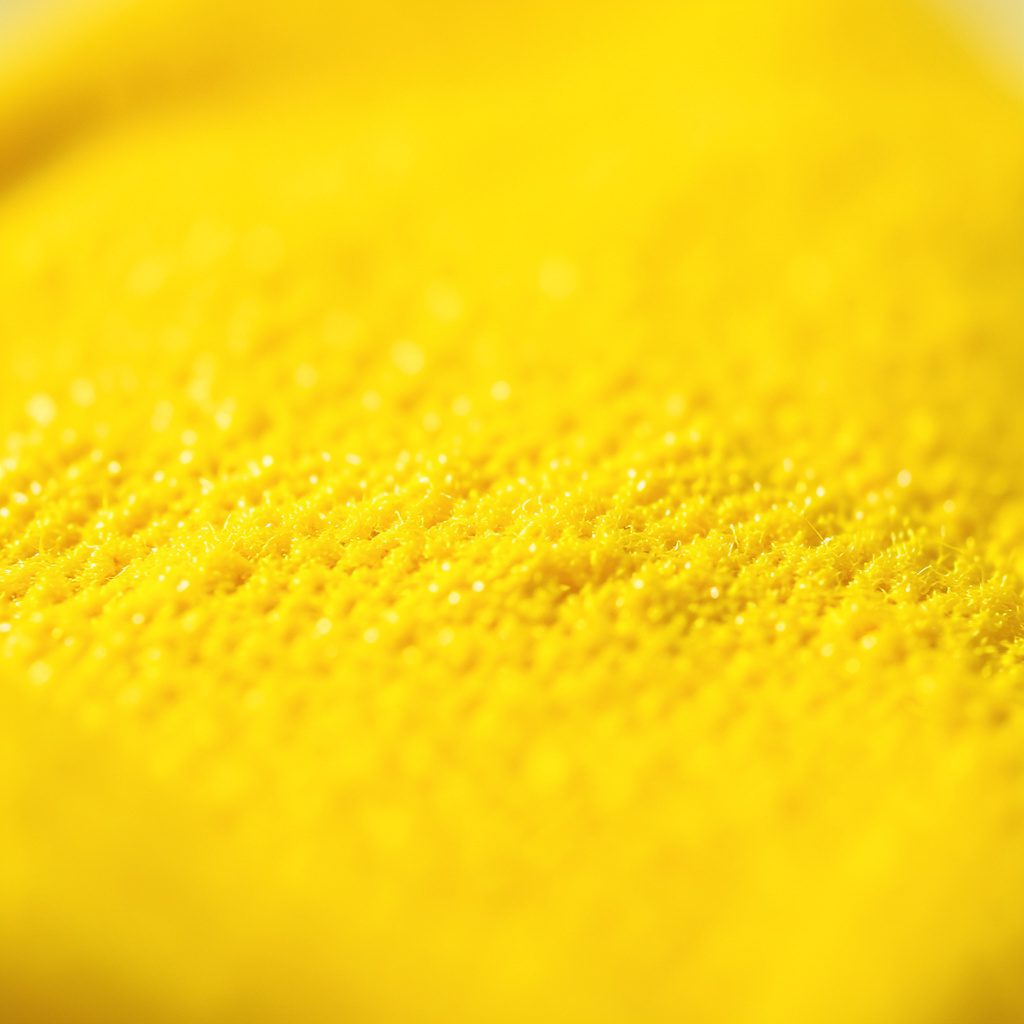 Extreme close-up of a smooth dark phone screen reflecting warm golden light, abstract digital surface in deep black and amber tones